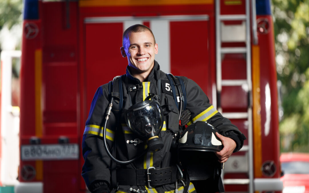 Photo of happy fireman with gas mask and helmet near fire engine
